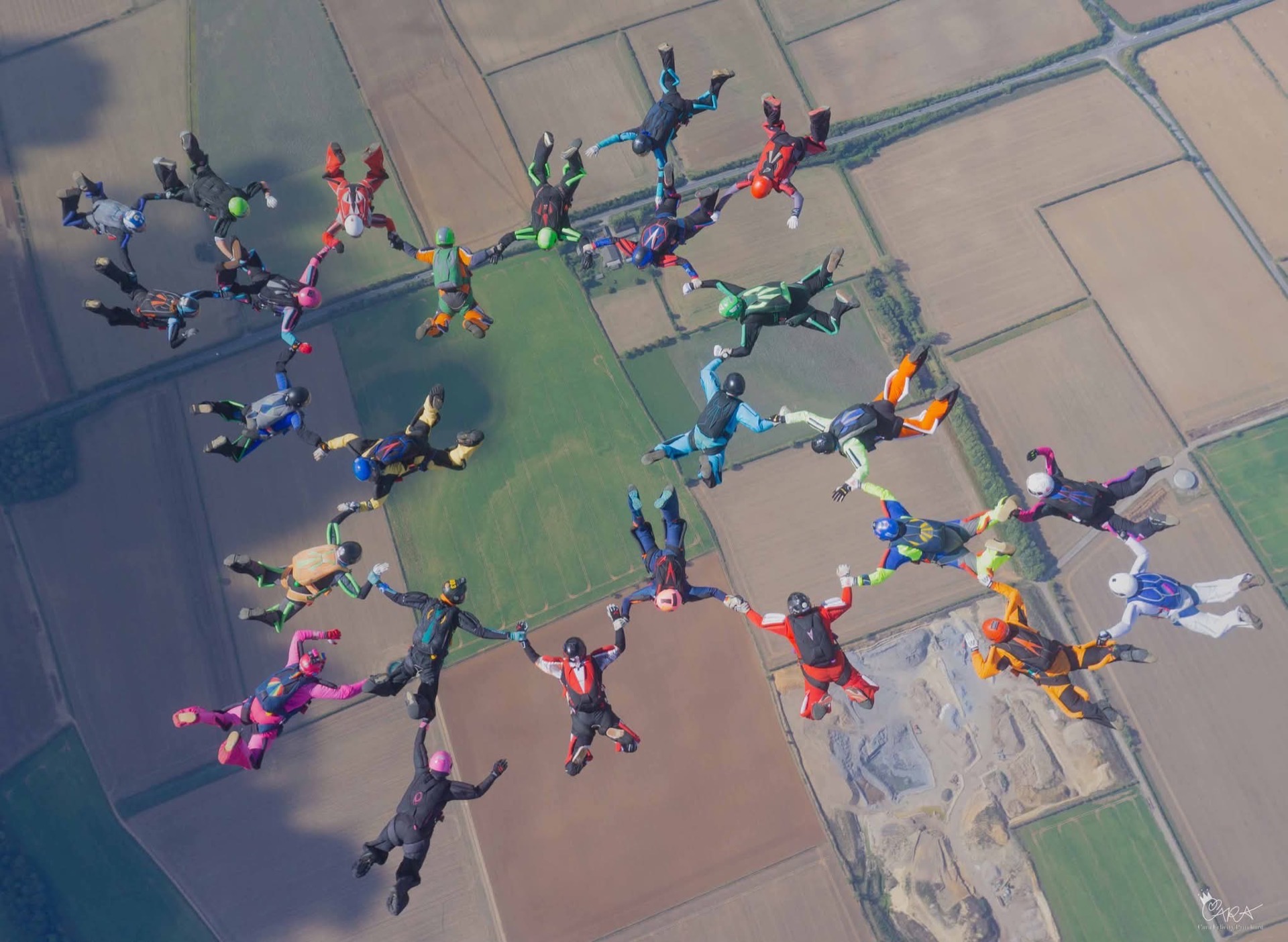 Formación de paracaidistas vista desde arriba sobre campos de cultivo